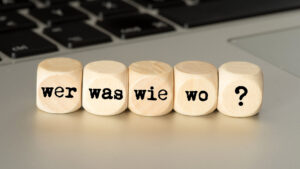 Ein Computer und Würfeln mit den Fragen, Wer, Was, Wie, Wo